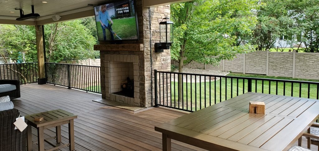 On a custom deck with patio furniture and TV playing.