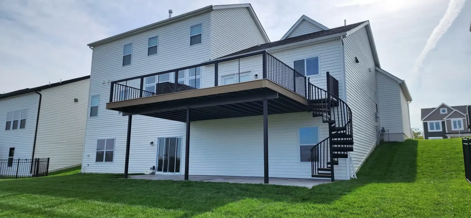 A second story deck with a spiral staircase leading to the ground below. The deck features a cable railing system with aluminum posts, offering a modern and sleek look.