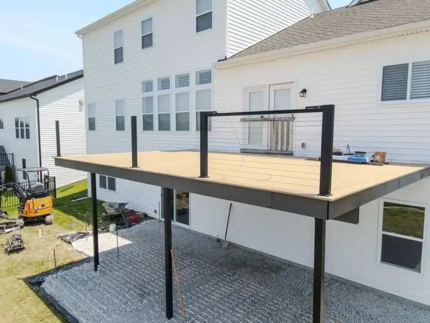 Photo of two-story white home with covered patio, construction equipment, and backyard lawn in progress.