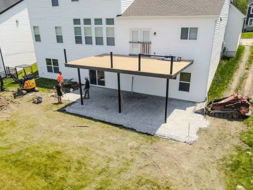 Photo of two-story white home with covered patio, construction equipment, and backyard lawn in progress.